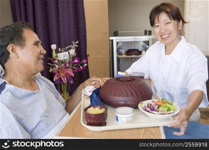 Nurse Serving A Patient A Meal In His Bed