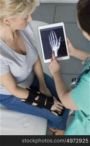 Nurse showing x-ray on digital tablet to mature patient at hospital