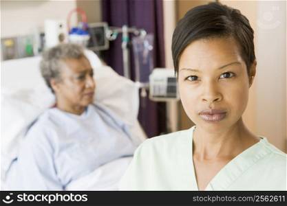 Nurse Standing In Patients Room Looking Serious