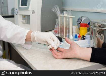 nurse stops bleeding with a swab after she collects blood specimen from a finger