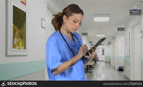 Nurse takes notes on clipboard outside room