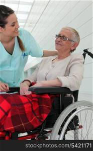Nurse talking to an elderly lady in a wheelchair