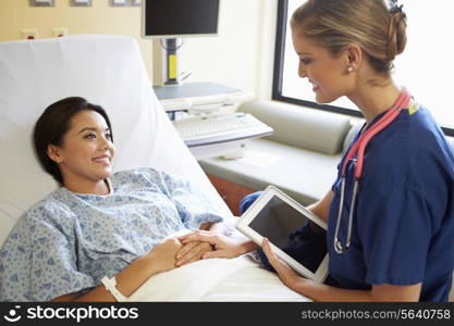 Nurse Talking To Female Patient On Ward Using Digital Tablet