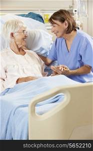 Nurse Talking To Senior Female Patient In Hospital Bed