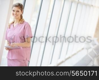 Nurse Using Digital Tablet In Corridor Of Modern Hospital