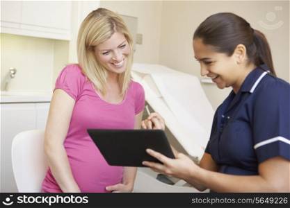Nurse Using Digital Tablet In Meeting With Pregnant Woman