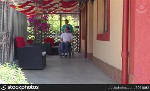 Nurse walking with male patient in a wheelchair outdoors
