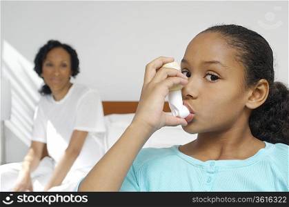 Nurse watching girl (7-9) using inhaler in hospital
