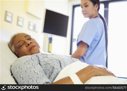 Nurse Watching Sleeping Senior Woman Patient In Hospital