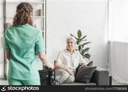nurse with wheelchair standing ion front happy female patient