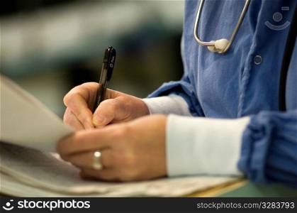Nurse writing on patient&acute;s chart.
