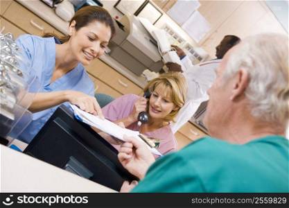 Nurses Discussing A Clipboard At The Reception Area In A Hospital