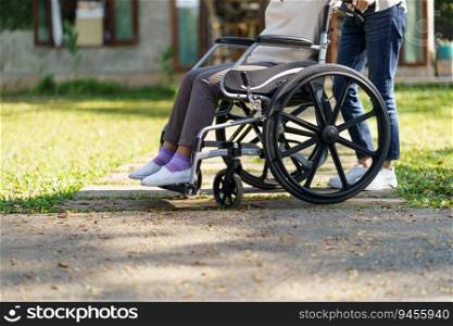 Nursing home. Young caregiver helping senior woman in wheelchair