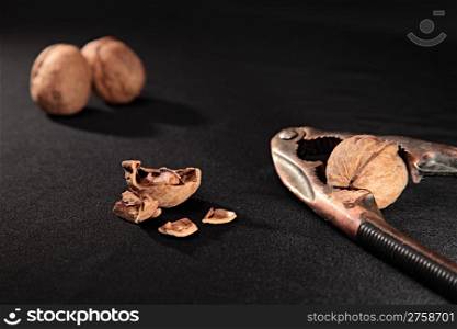 nutcracker, whole and chopped nuts on black background