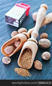 nutmeg spice in wooden spoon and on a table