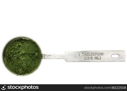 Nutrient-rich organic spirulina powder - isolated measuring metal tablespoon, top view