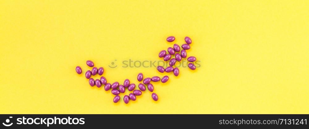 Nutritional supplement purple pills isolated on bold yellow background with copy space. Template for feminine beauty blog social media. Female healthcare concept