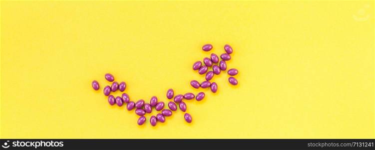 Nutritional supplement purple pills isolated on bold yellow background with copy space. Template for feminine beauty blog social media. Female healthcare concept