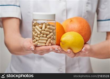 nutritionist doctor healthy lifestyle concept - holding fresh organic citrus fruits - grapefruit, orange, lemon and can of vitamin capsules.. nutritionist doctor healthy lifestyle concept - holding fresh organic citrus fruits - grapefruit, orange, lemon and can of vitamin capsules