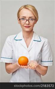 nutritionist doctor healthy lifestyle concept - holding fresh organic orange fruit and vitamin capsules.. nutritionist doctor healthy lifestyle concept - holding fresh organic orange fruit and vitamin capsules