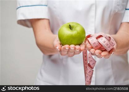 nutritionist doctor healthy lifestyle concept - holding organic fresh green apple and measure tape.. nutritionist doctor healthy lifestyle concept - holding organic fresh green apple and measure tape