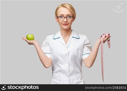 nutritionist doctor healthy lifestyle concept - holding organic fresh green apple and measure tape.. nutritionist doctor healthy lifestyle concept - holding organic fresh green apple and measure tape