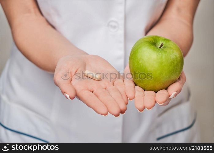 nutritionist doctor healthy lifestyle concept - holding organic fresh green apple and vitamin capsules.. nutritionist doctor healthy lifestyle concept - holding organic fresh green apple and vitamin capsules