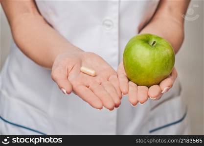 nutritionist doctor healthy lifestyle concept - holding organic fresh green apple and vitamin capsules.. nutritionist doctor healthy lifestyle concept - holding organic fresh green apple and vitamin capsules