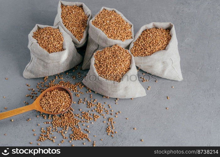 Nutritious ingredient containing vitamins. Shot of linen sacks with buckwheat against grey background. Organic food. Healthy nutrition