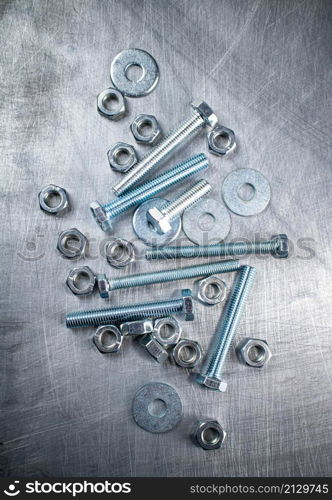 Nuts and bolts on the table. On a gray background. High quality photo. Nuts and bolts on the table.