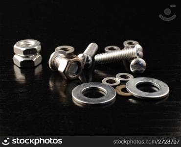 Nuts, screws and washers on a black background