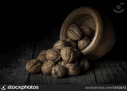 nuts spilled from a wooden bowl on a black background
