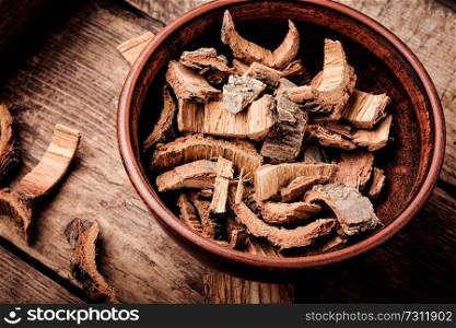 Oak bark in bowl on dark wooden table. Oak in herbal medicine.Herbs medicine. Dry oak bark