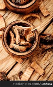 Oak bark in mortar on a dark wooden table. Oak in herbal medicine.Medicinal plant oak.. Dry oak bark