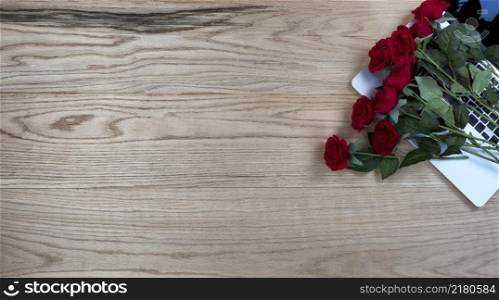 Oak wood office desk table with lovely red roses on top of a laptop computer for a Valentines day gift at work or school.