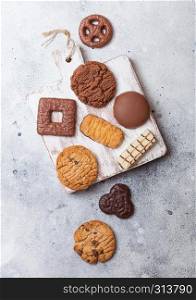 Oat and chocolate cookies selection on wooden board on stone kitchen background