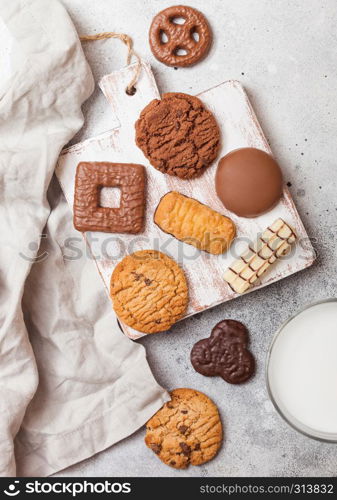 Oat and chocolate cookies selection with glass of milk on wooden board on stone kitchen background