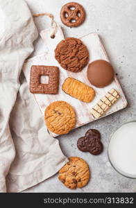 Oat and chocolate cookies selection with glass of milk on wooden board on stone kitchen background