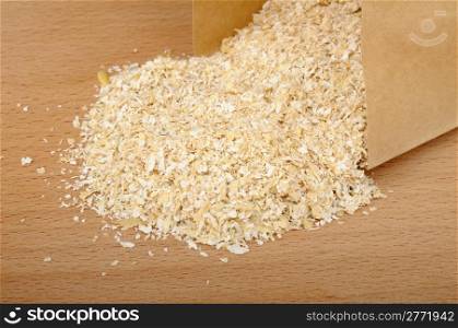 oat bran in a paper bag on a wooden background