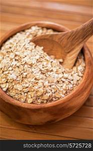 Oat flakes at wooden plate on wooden background