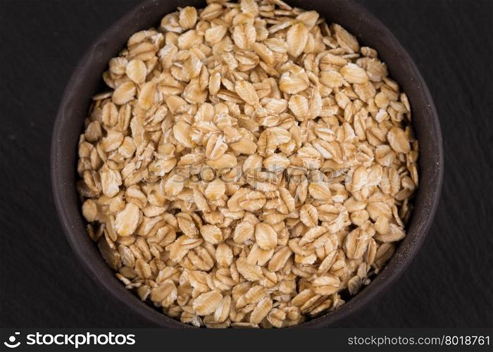 oat flakes in bowl on a dark stone board