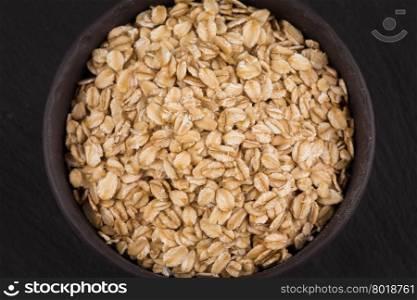 oat flakes in bowl on a dark stone board