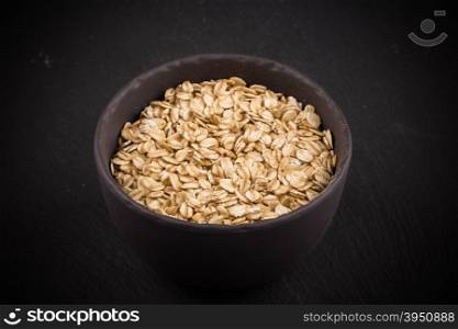 oat flakes in bowl on dark stone plate