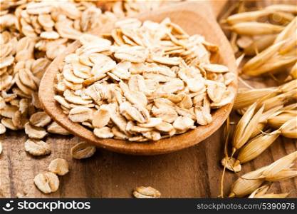 Oat flakes in spoon on wooden table