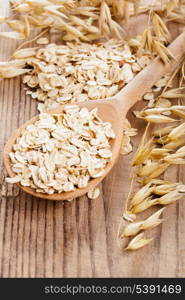 Oat flakes in spoon on wooden table