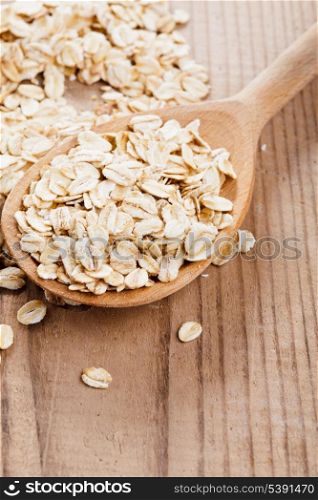 Oat flakes in spoon on wooden table