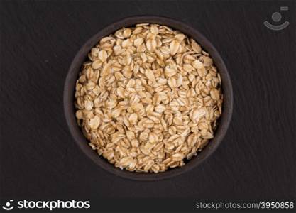 oat flakes in stone bowl on dark background
