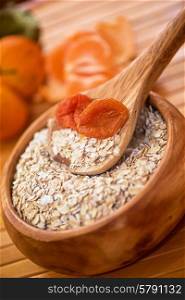 Oat flakes. Oat flakes with dried apricots at wooden plate on wooden background