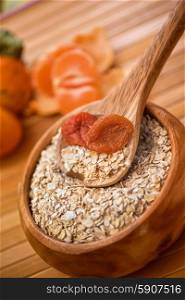 Oat flakes. Oat flakes with dried apricots at wooden plate on wooden background