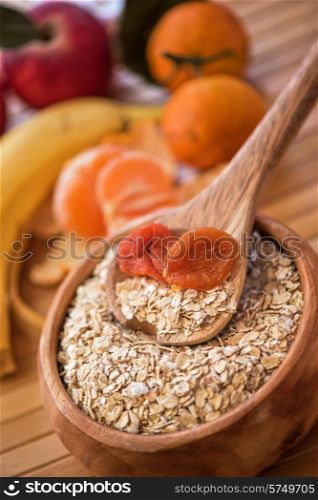 Oat flakes with dried apricots at wooden plate on wooden background. Oat flakes